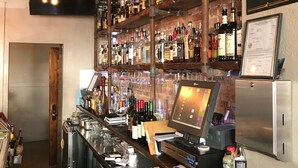 A bar area with shelves of liquor bottles, a cash register, and a sign stating "we reserve the right to refuse service to anyone".
