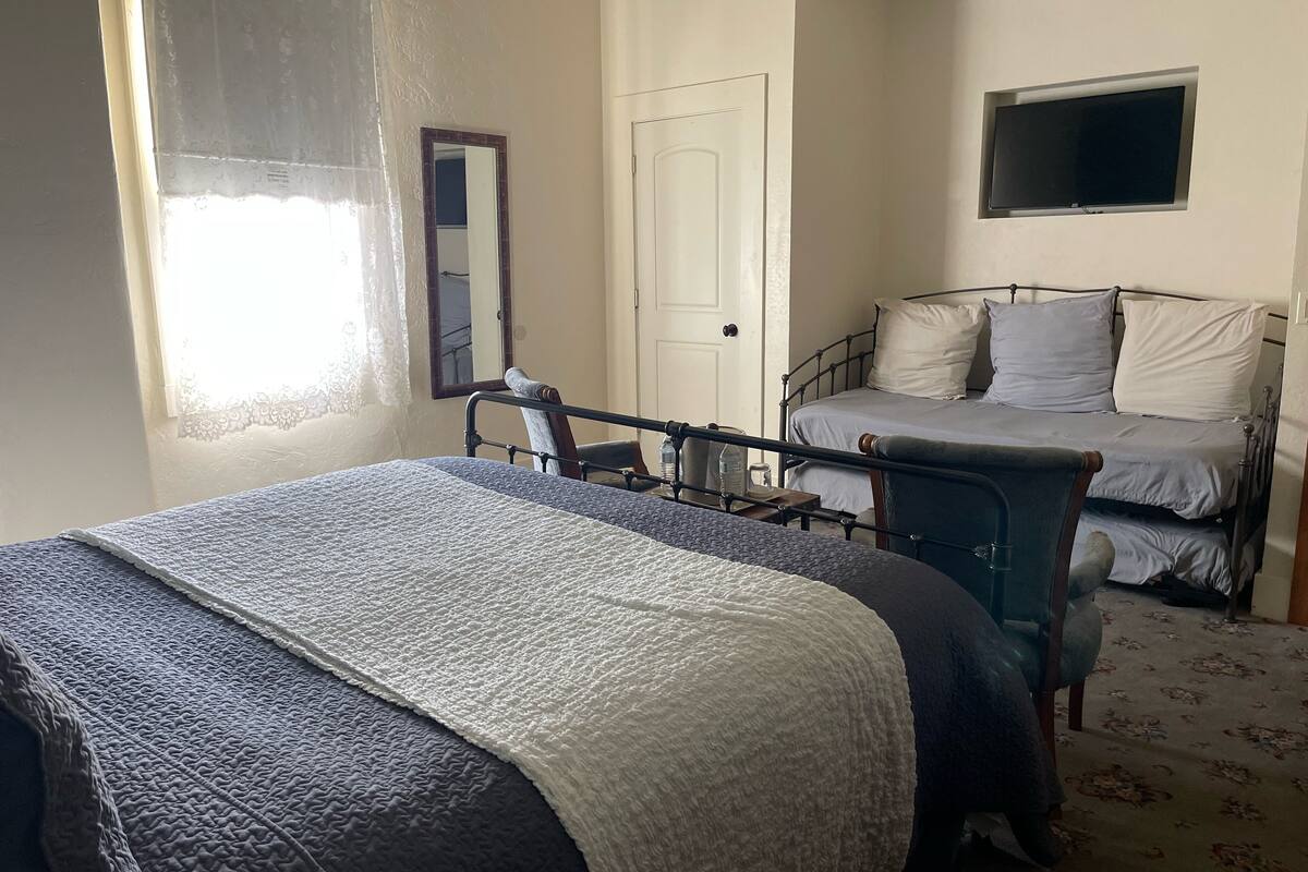 A bedroom with a bed, a chair, a TV, and a door.