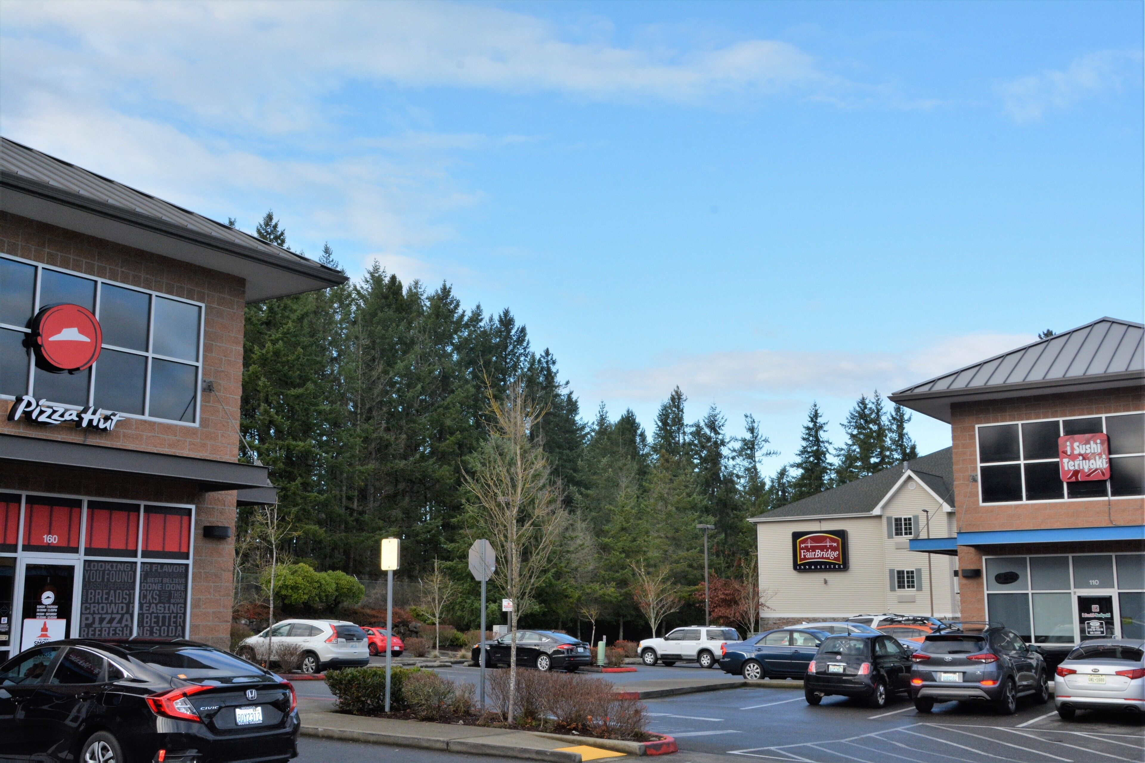 Un parking avec plusieurs voitures, un restaurant Pizza Hut et un bâtiment Fairbridge.