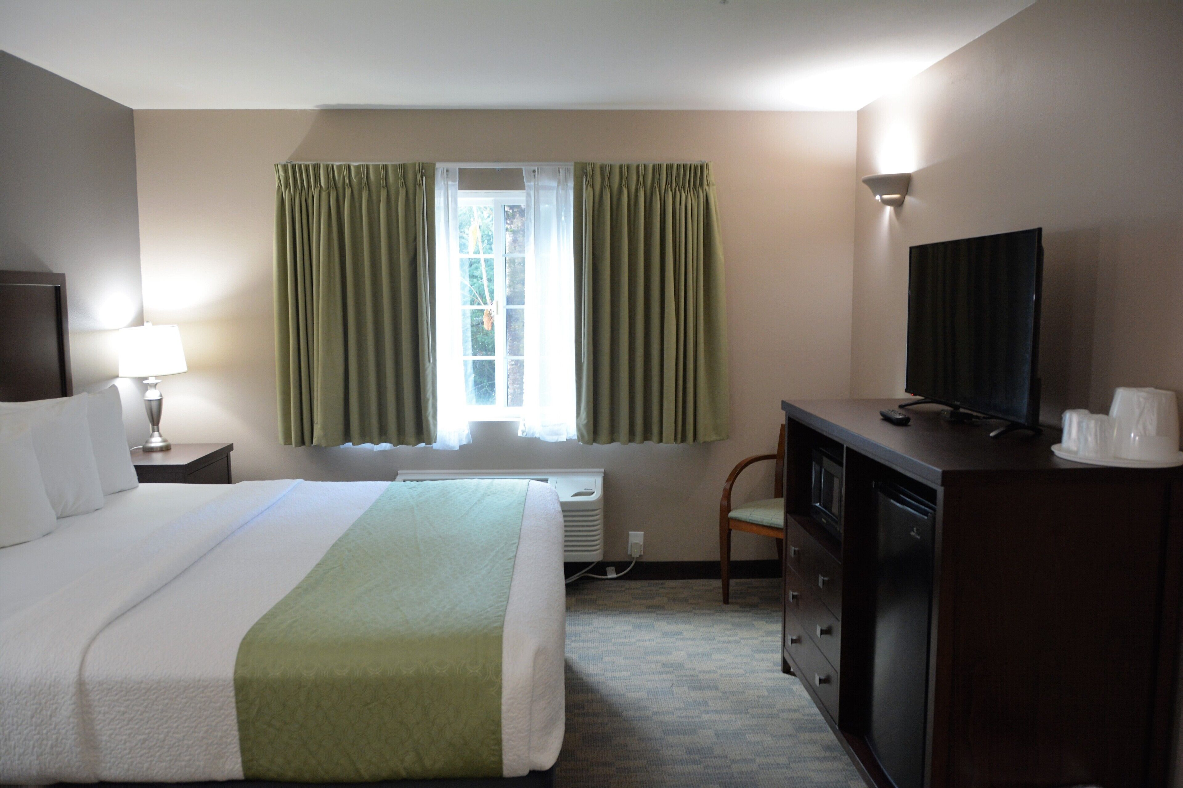 Een hotelkamer met een bed, een televisie, een bureau en een stoel.