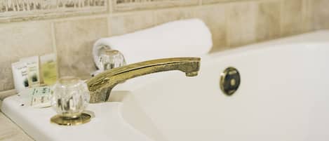 A bathtub with a brass faucet and a glass stopper.