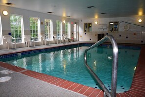 An indoor swimming pool with clear water, a pool ladder, and white chairs along the side. - FairBridge Inn & Suites Dupont (Dupont)