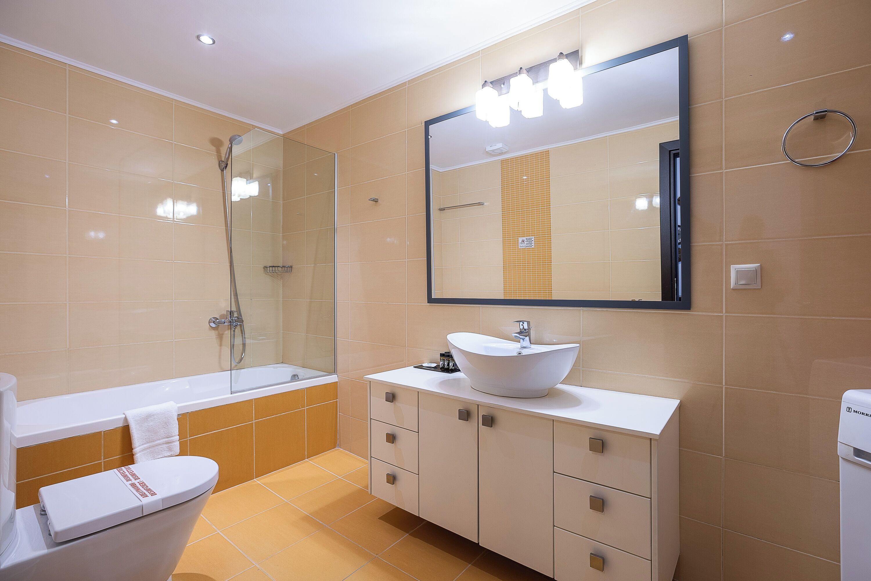 Een moderne badkamer met een badkuip, toilet, wastafel en een grote spiegel.
