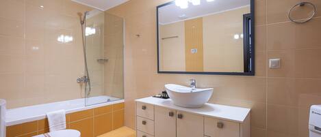 Een moderne badkamer met een badkuip, toilet, wastafel en een grote spiegel.