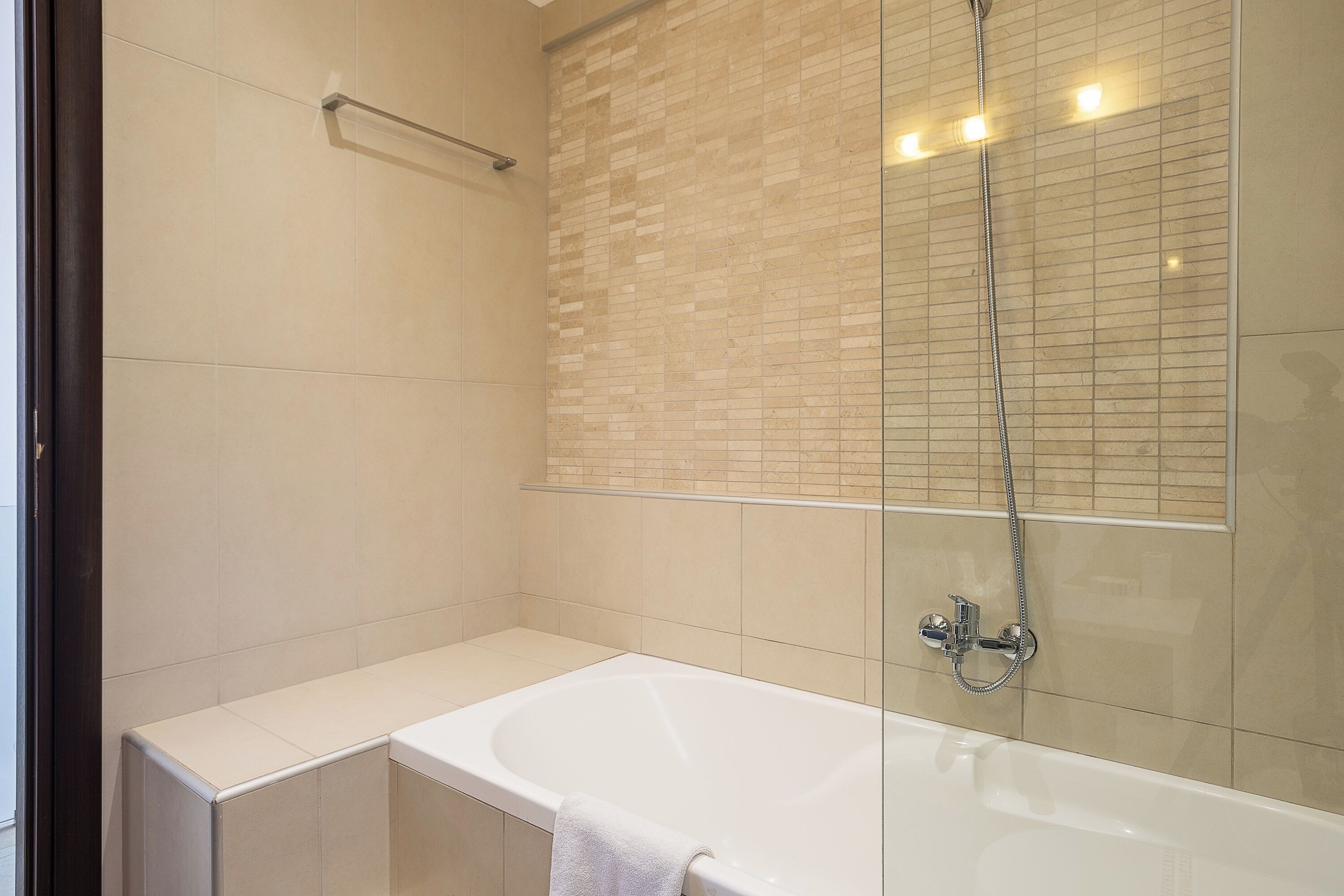 A modern bathroom with a bathtub, a glass-enclosed shower, and a towel rack.
