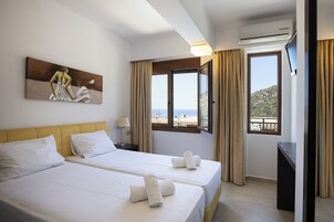 Habitación de hotel con dos camas, un cuadro en la pared, una ventana con vistas y un equipo de aire acondicionado.