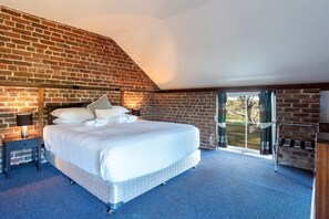 A bedroom with a large bed, a nightstand with a lamp, and a view of the outdoors through a glass door. - Coolangatta Estate (Coolangatta)