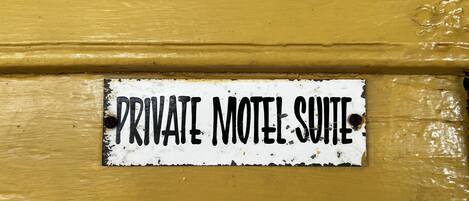 Un letrero en una pared amarilla que dice "PRIVATE MOTEL SUITE".