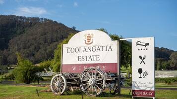 A sign for Coolangatta Estate Winery with a vintage carriage and a sign indicating it is open daily.