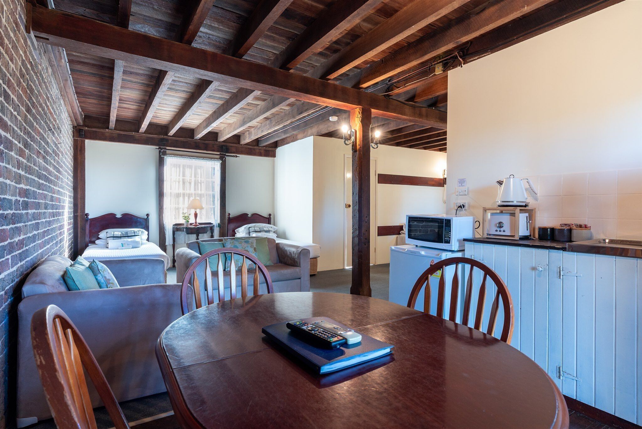 Una habitación acogedora con una mesa de comedor de madera, un sofá y una zona de cocina con microondas y tostadora.