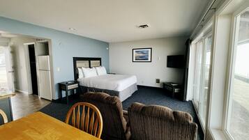 A hotel room with a bed, a desk, a chair, a TV, and a window.