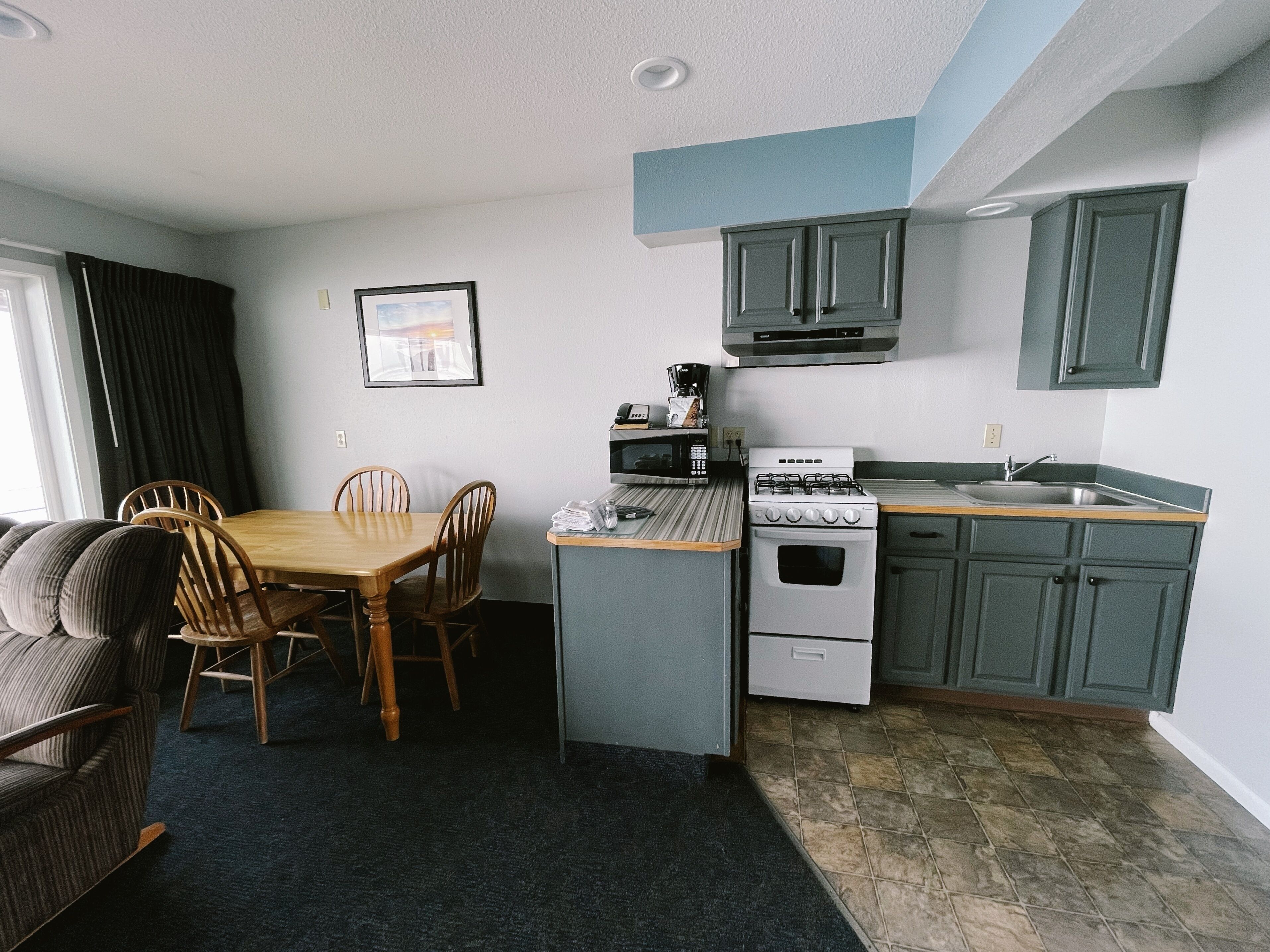 A compact kitchen with a dining area, a stove, and a microwave.