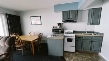 A compact kitchen with a dining area, a stove, and a microwave.