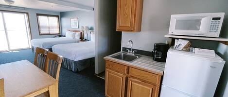 Une chambre d’hôtel compacte comprenant un coin cuisine, un espace repas et deux lits simples.