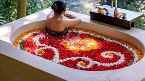A person sitting in a bathtub filled with colorful flower petals, surrounded by lush greenery. - The Lokha Ubud Resort, Villas & SPA (Ubud)