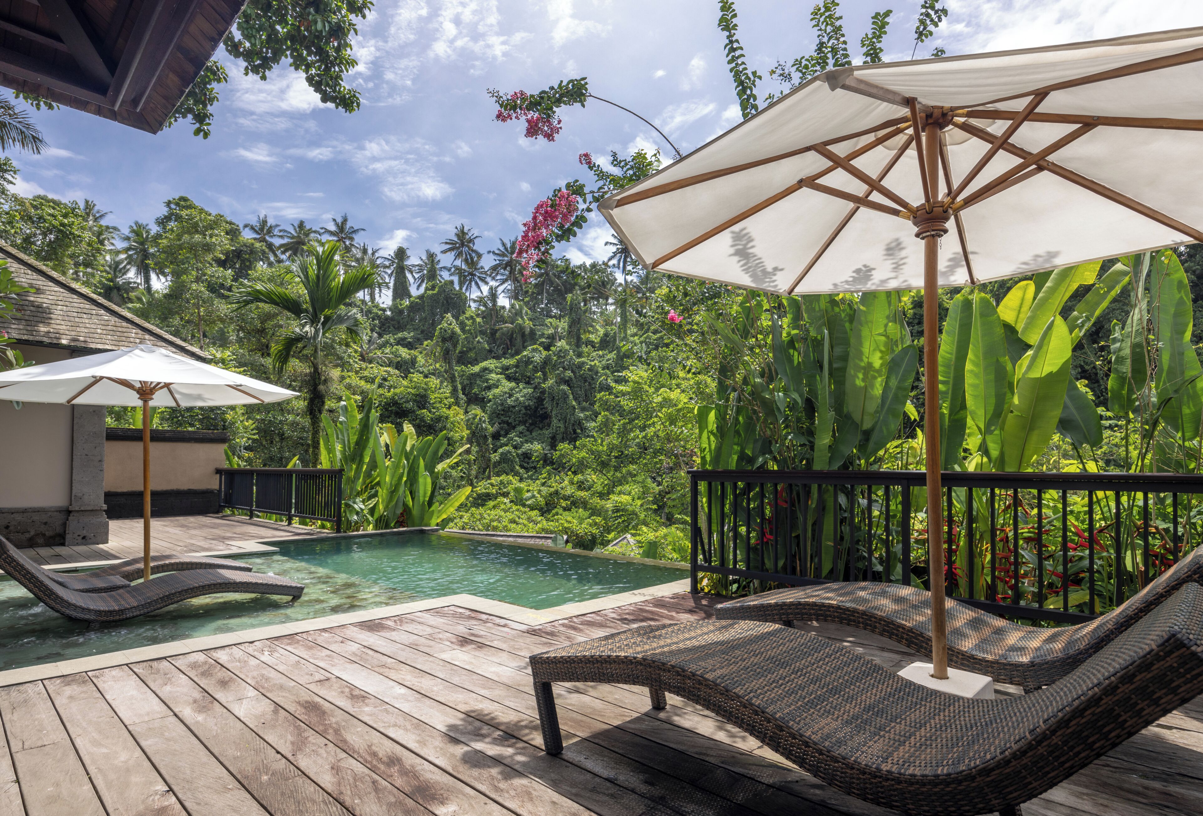 A wooden deck with a pool, lounge chairs, and an umbrella.