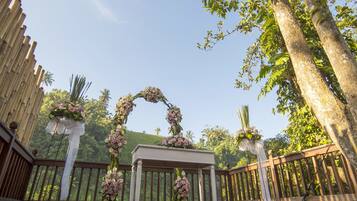 A wooden deck with a floral archway and a white column.