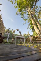 A wooden deck with a floral archway and a white column.