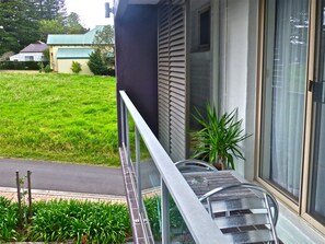 A modern building with a balcony, a grassy yard, and a neighboring house. - Park Ridge Retreat (Gerringong)