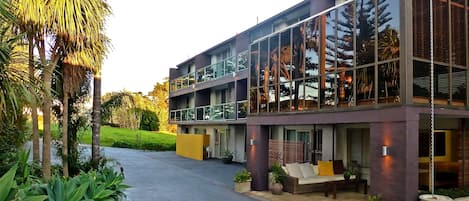 A modern building with a glass facade, a covered outdoor seating area, and a well-maintained garden.