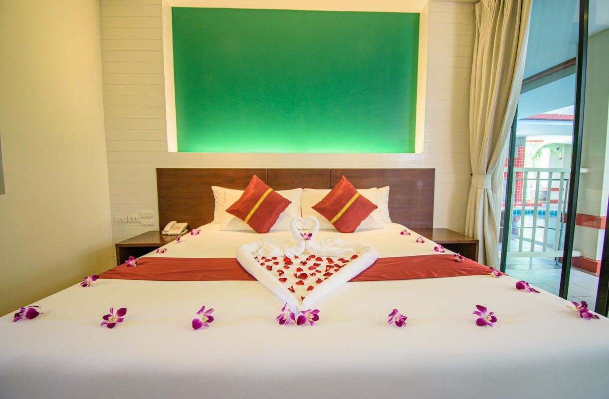 A hotel room with a large bed, a green wall, and a view of a building outside.