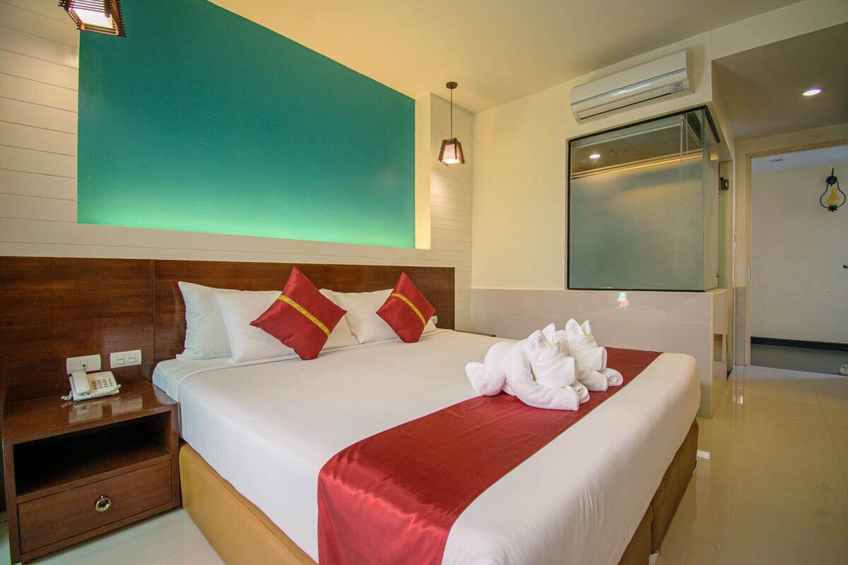 A hotel room with a large bed, a bedside table with a phone, and a red and white bedspread.