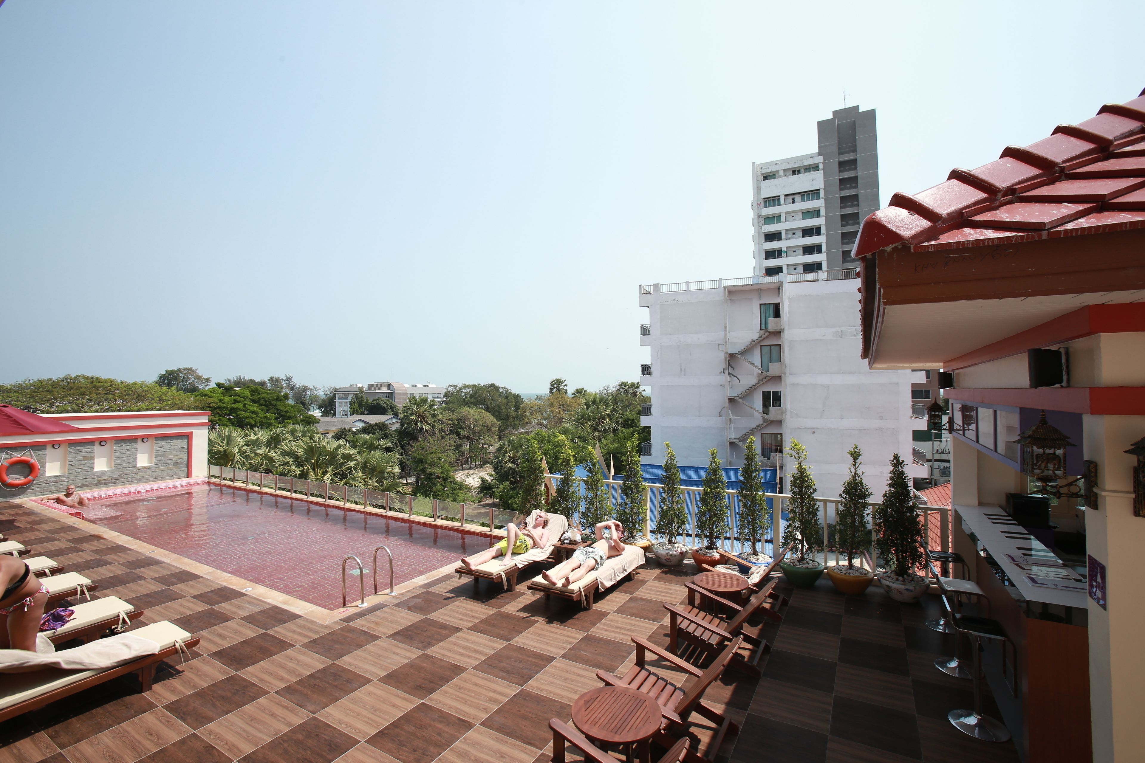 A rooftop pool area with lounge chairs and a bar.