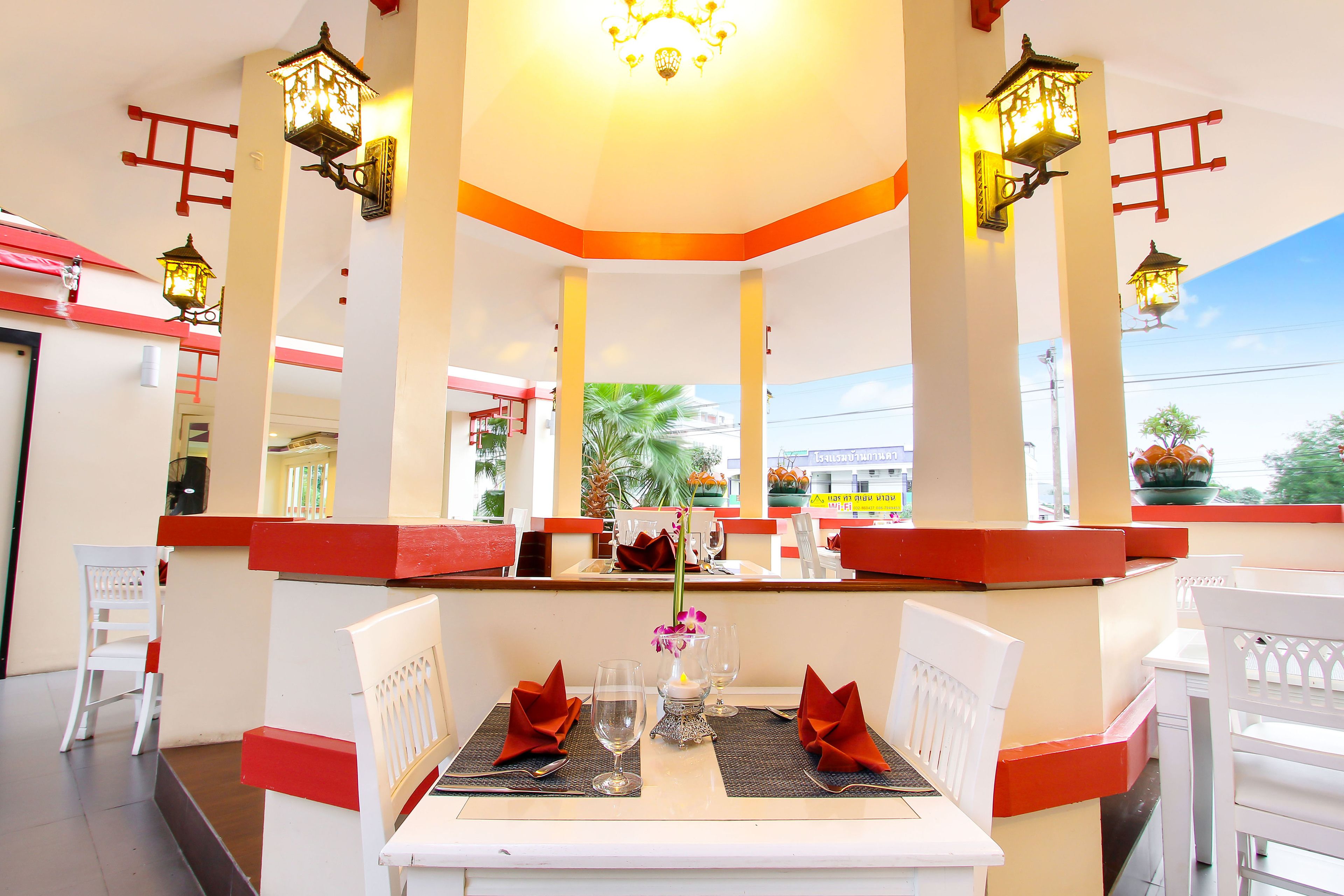 Ein Restaurant mit weiß-roter Dekoration, gedeckten Tischen und hängenden Laternen.