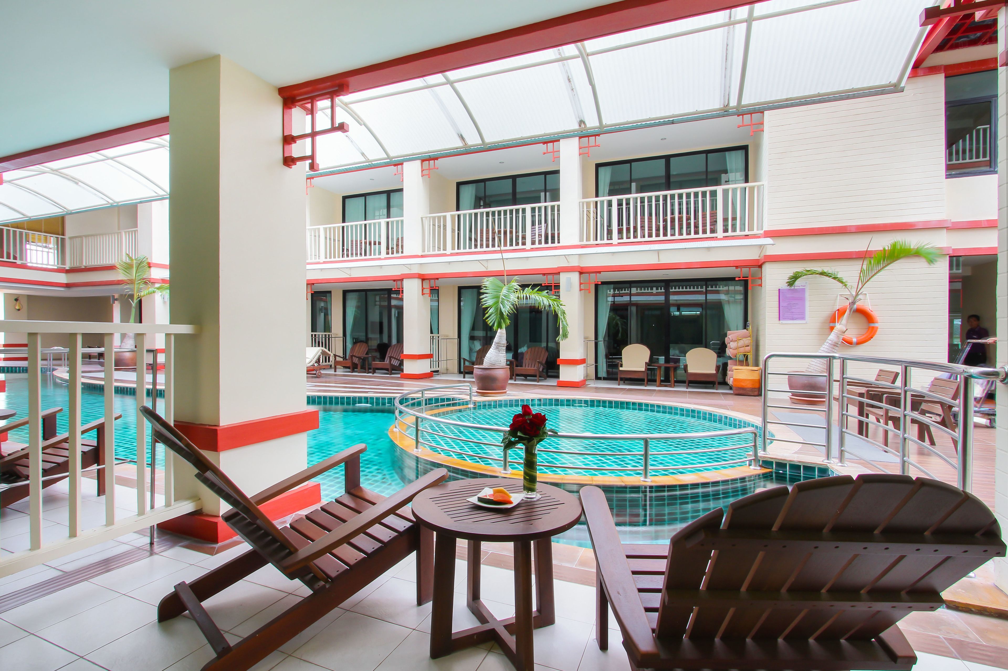 A multi-level indoor swimming pool with lounge chairs and tables, surrounded by balconies and a restaurant.