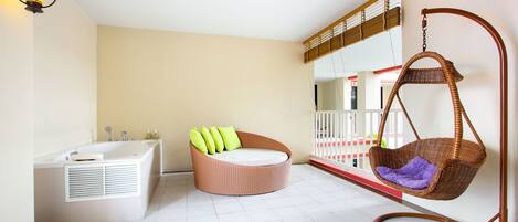 Un baño moderno con una bañera, un sillón redondo de mimbre con cojines y una hamaca colgante de mimbre.