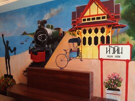Un mural con un tren, una casa y un letrero que dice 'HUA HIN'.
