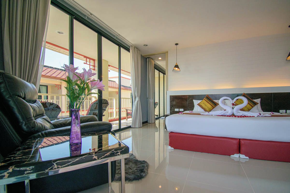 Habitación de hotel con una cama grande, un sofá de cuero, una mesa de centro de vidrio y vistas al exterior.