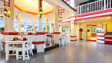 A spacious hotel lobby with a central seating area, a reception desk, and a view of the outside.