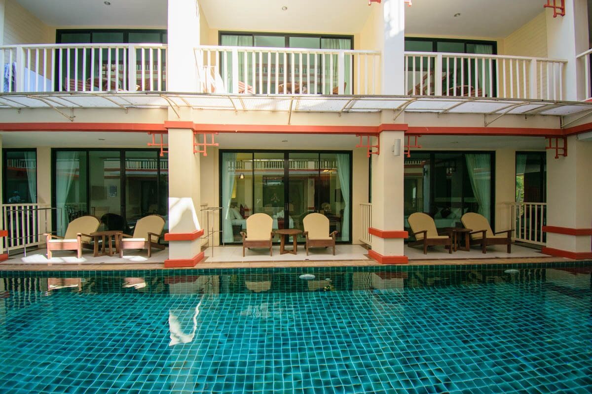 A hotel with a swimming pool, outdoor seating, and a balcony.