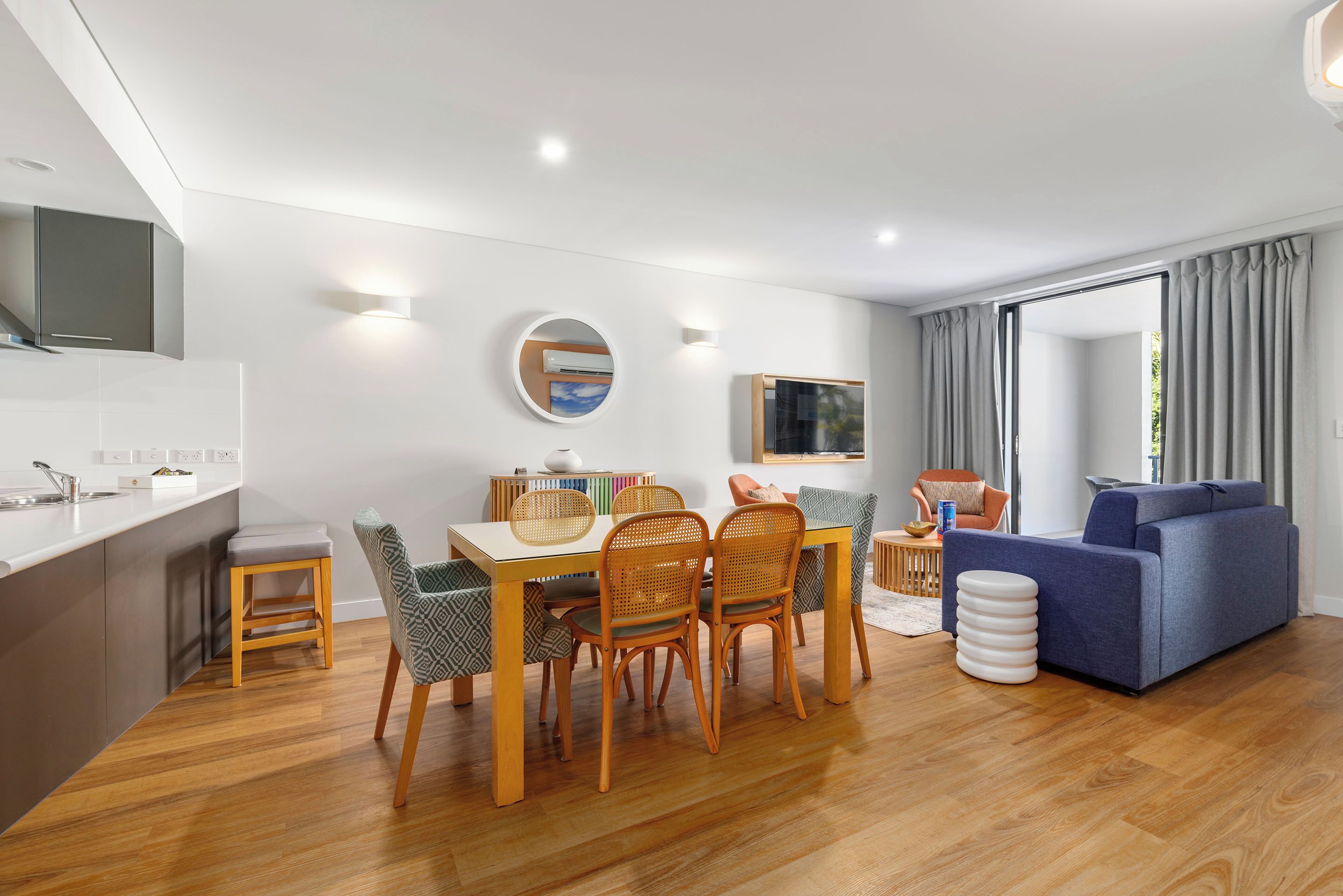 A modern living space with a dining area, kitchen, and seating area.