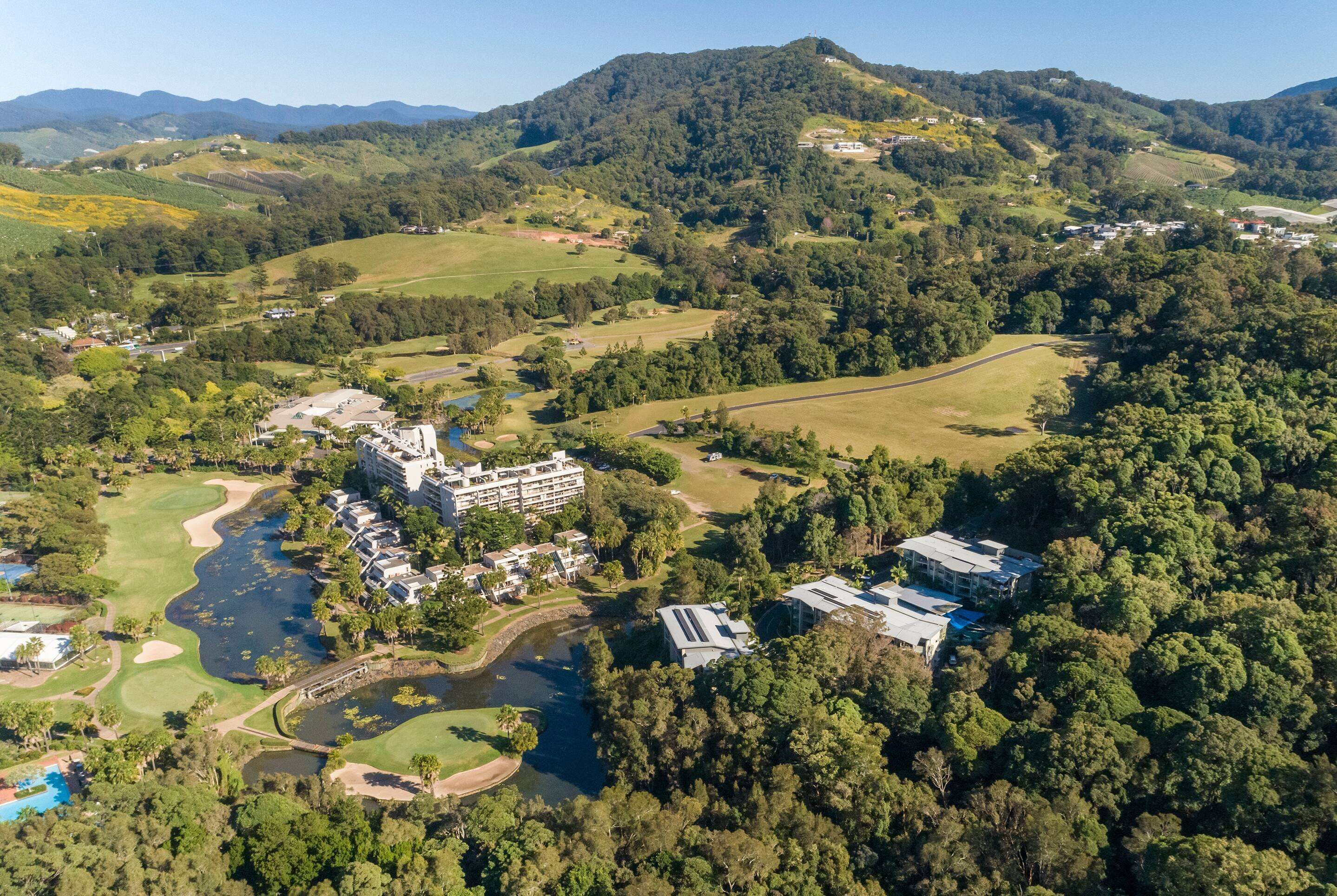 Luchtbeeld van een resort met een golfbaan, een rivier en omliggende beboste heuvels.