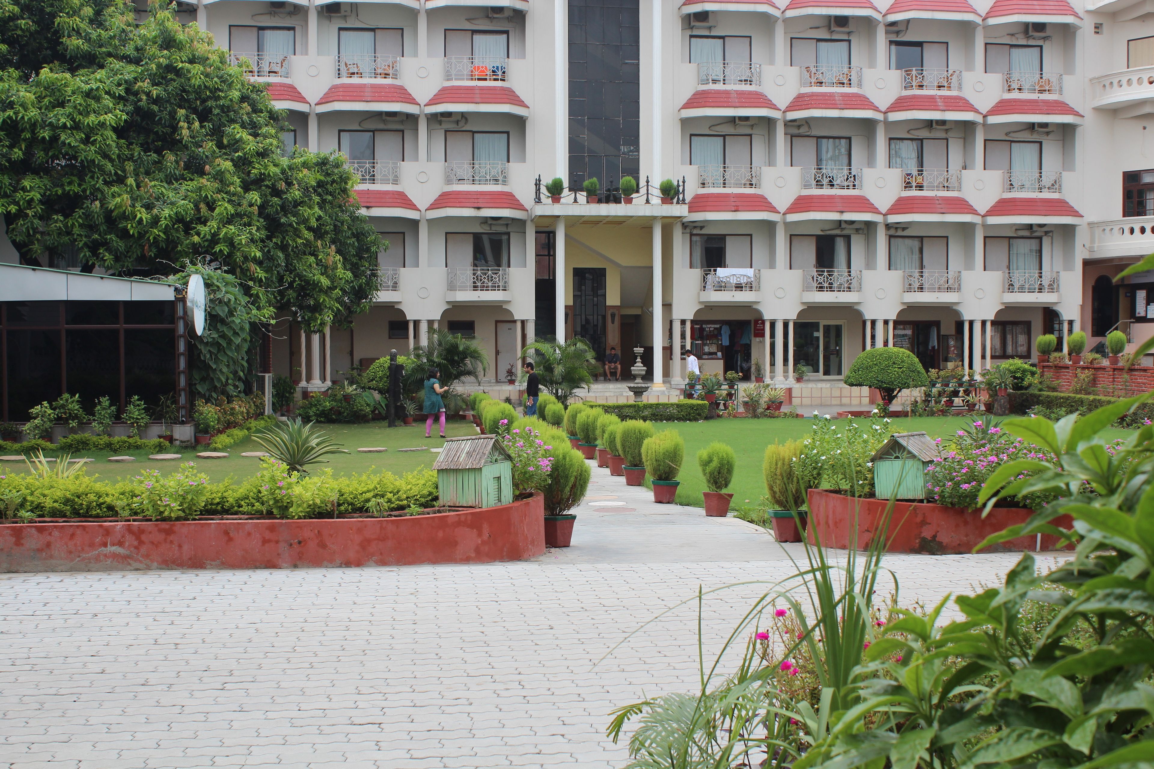 A hotel courtyard with a central pathway, potted plants, and a fountain.