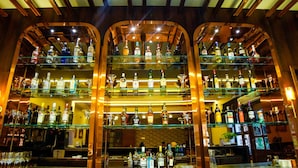 Eine Bar mit mehreren Regalen voller Spirituosenflaschen und Gläsern.