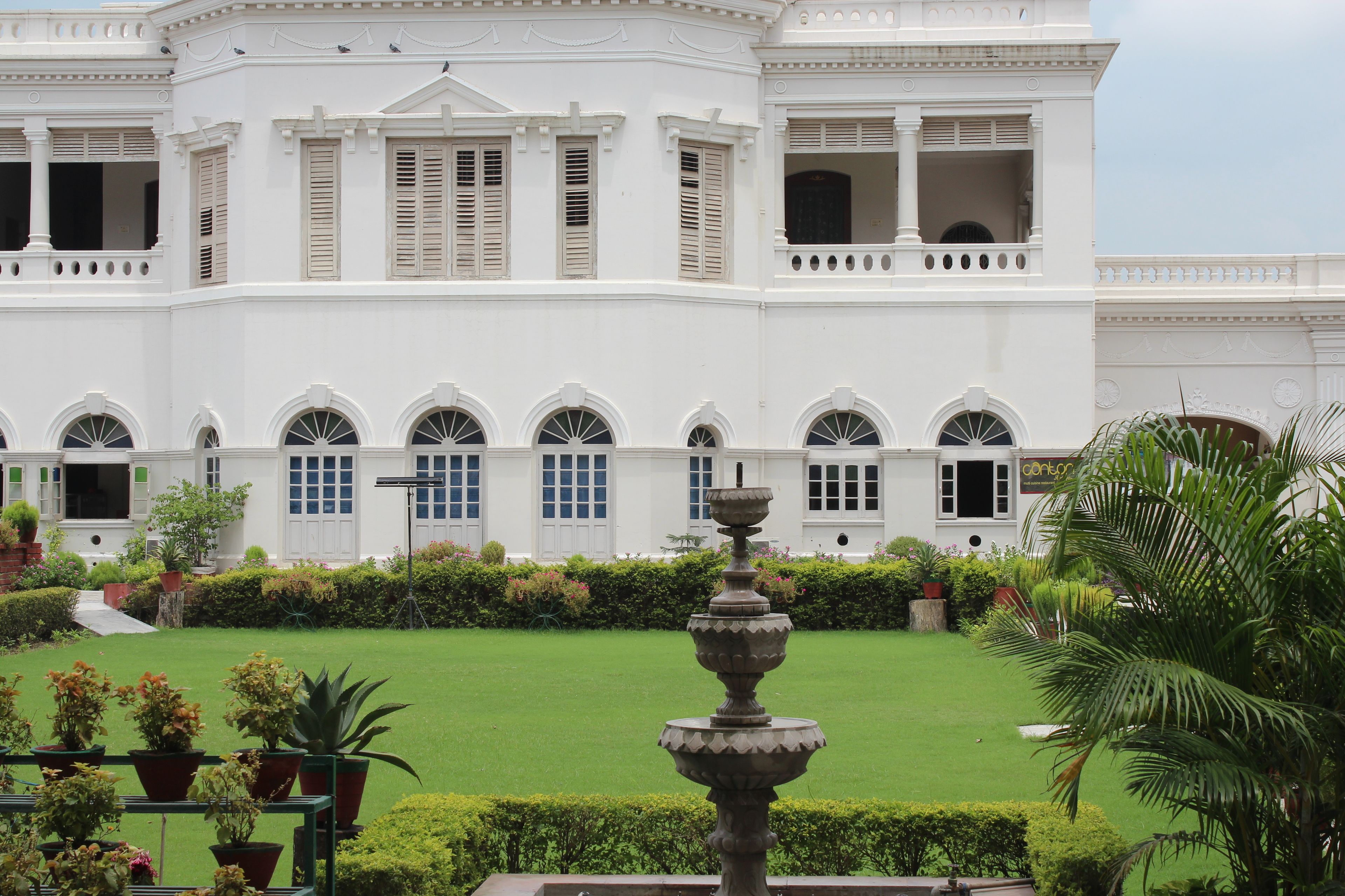 A large white building with arched windows and a central fountain.