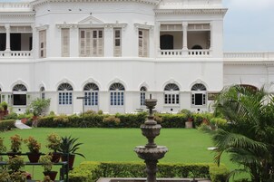 A large white building with arched windows and a central fountain.