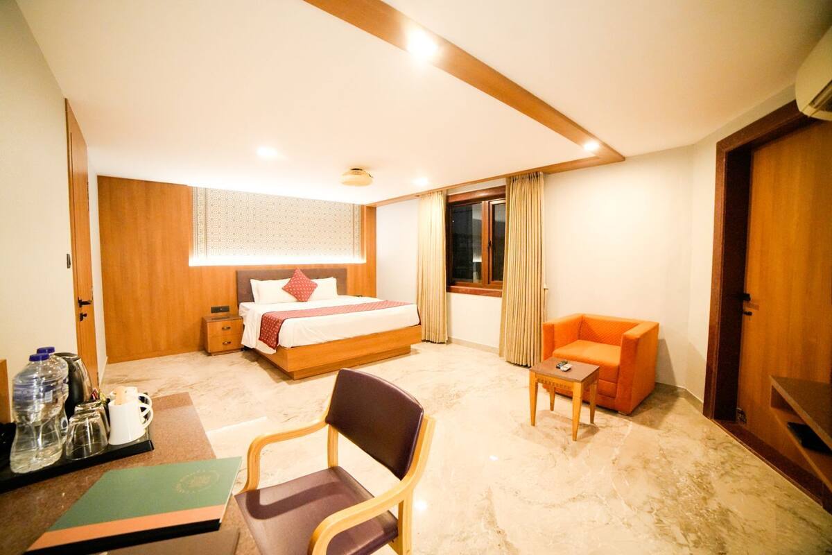 A hotel room with a bed, a chair, a small table, and a window.