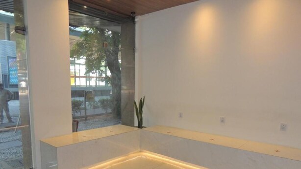 A modern reception area with a glass partition, a bench, and a potted plant. - Hotel Esplanada (Belo Horizonte)