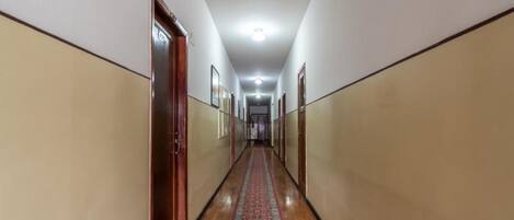 Un pasillo largo y estrecho con piso de madera y alfombra estampada.