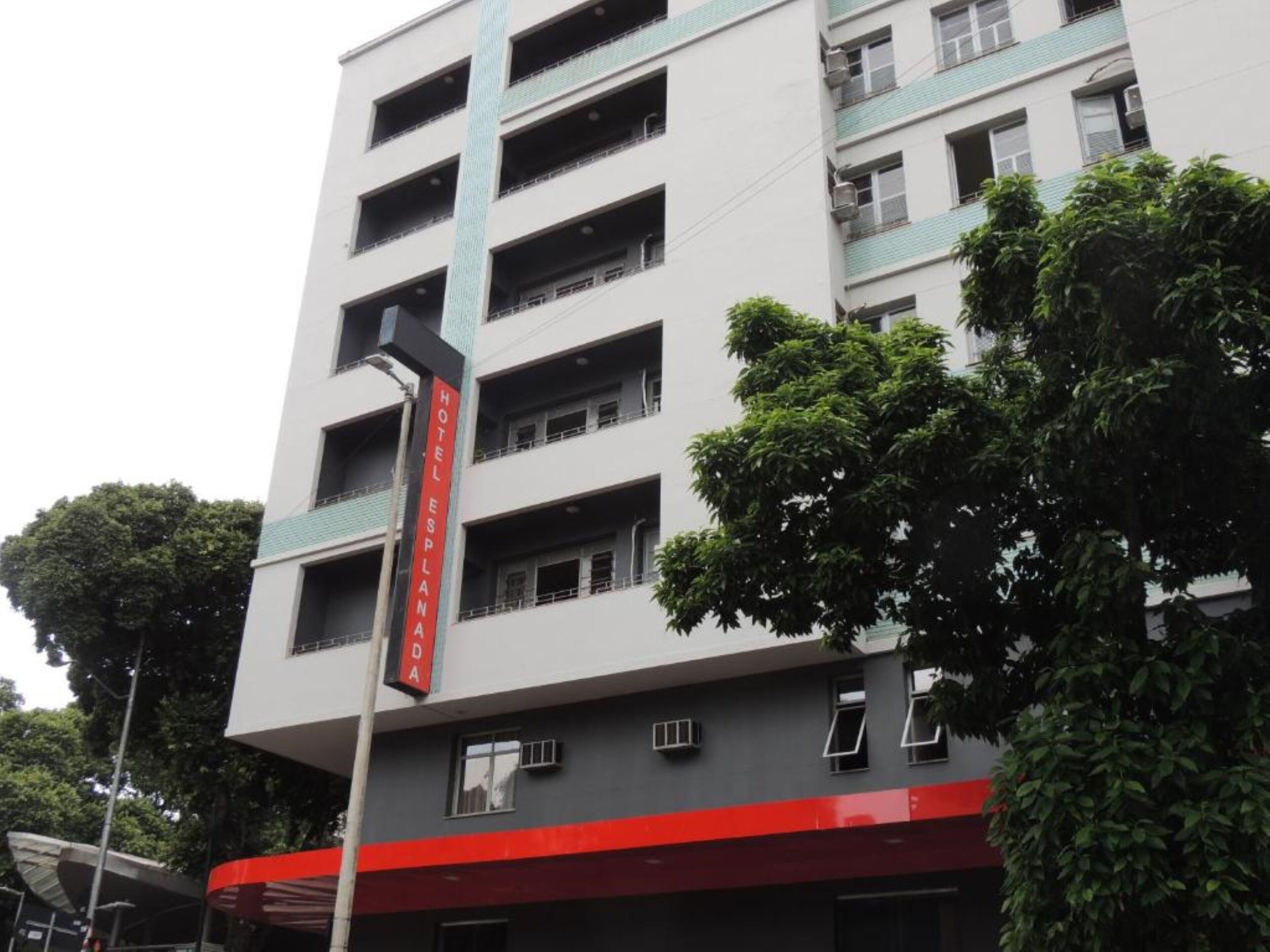Um hotel com vários andares e uma placa vermelha e branca que indica o nome.
