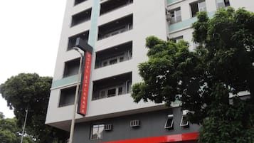 Um hotel com vários andares e uma placa vermelha e branca que indica o nome.