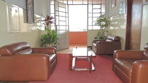 A spacious living room with leather sofas, a central coffee table, and potted plants. - Hotel Esplanada (Belo Horizonte)