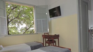 A room with two beds, a TV, a chair, and a window with shutters. - Hotel Esplanada (Belo Horizonte)