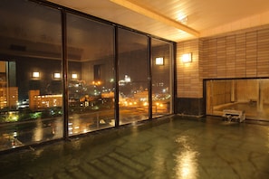 A spacious room with large windows offering a city view at night.