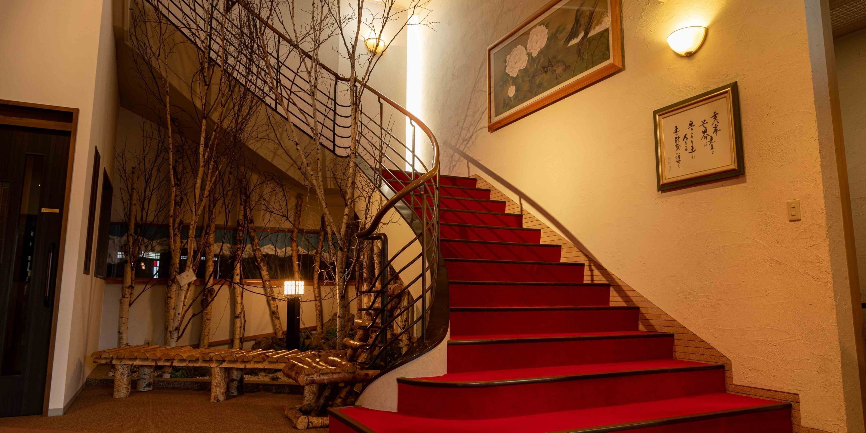 Un escalier avec des marches rouges, un banc en bois et un luminaire fixé au mur.