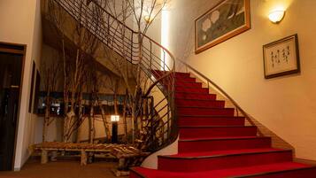 Un escalier avec des marches rouges, un banc en bois et un luminaire fixé au mur.